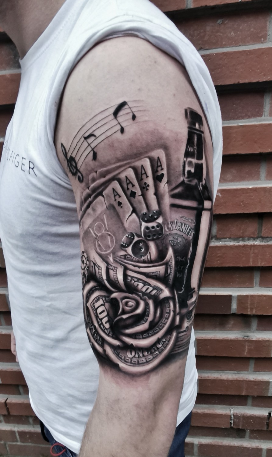 Realistic motif with cards, dice, and rose on the upper arm
