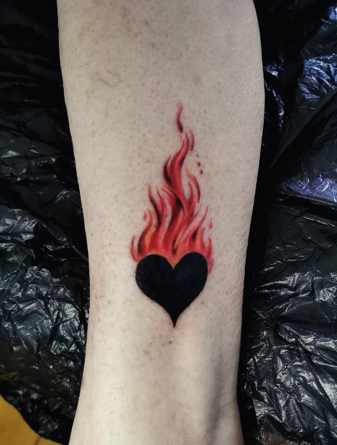 Small black heart with red flames