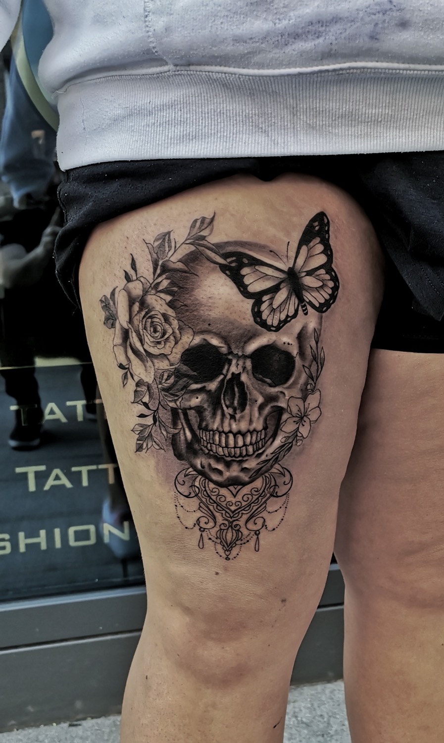 Skull with butterfly and roses on the thigh